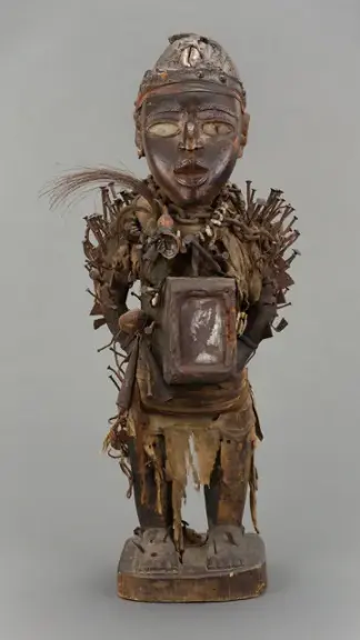 Male Figure (Nkisi Nkondi) — Wood, metal, glass, fabric, fiber, cowrie shells, bone, leather, gourd, and feathers