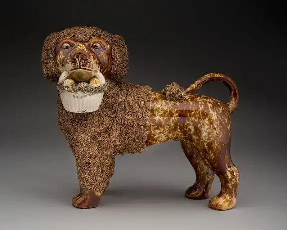 Mottled brown ceramic poodle with a basket in its mouth.