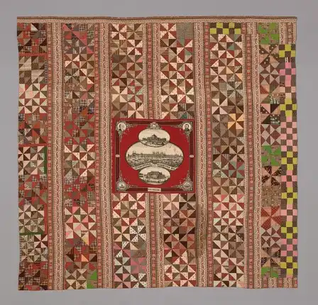Patchwork quilt with striped pinwheel blocks and a red Centennial panel.