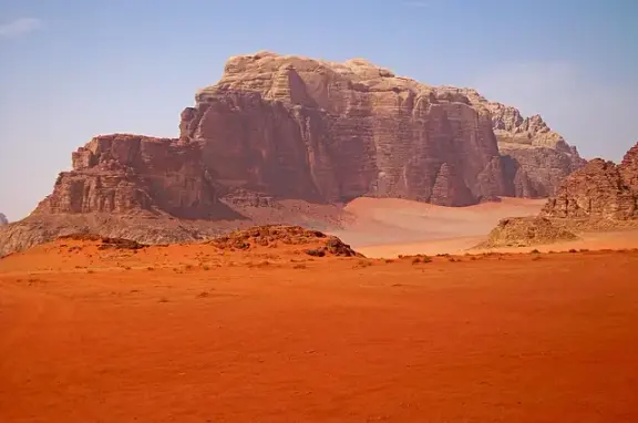 A sandstone mountain rising above the desert at Wadi Rum, Jordan.