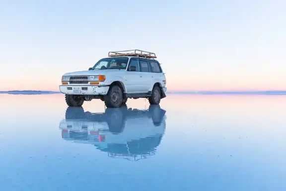 A vehicle reflected in shallow water on Bolivia's Salar de Uyuni salt flat.