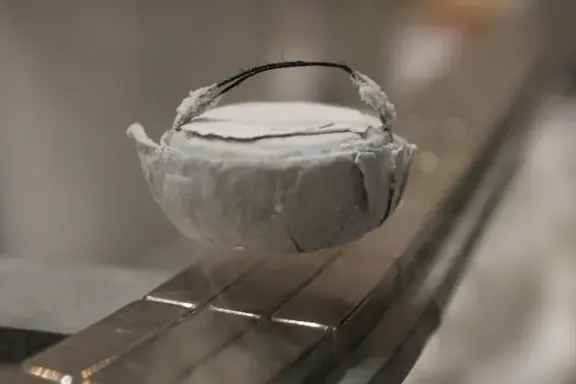 A cooled superconductor levitating above permanent magnets.