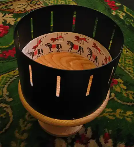 A modern replica of a Victorian zoetrope with viewing slits around its rotating drum.
