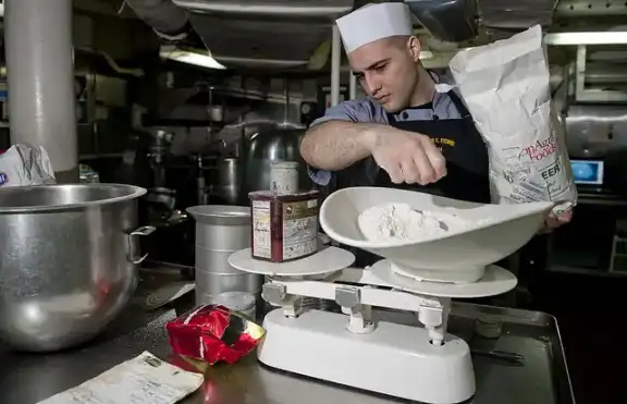 A baker weighing flour for a large batch of bread.