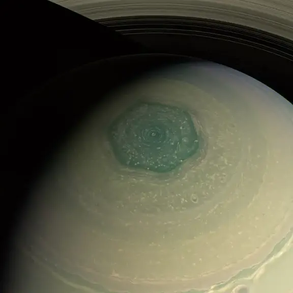 A view of Saturn and its hexagonal north-polar atmospheric pattern.