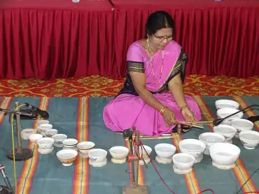 A musician playing a jal tarang made of tuned water-filled bowls.