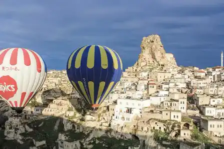 Hot-air balloons above Cappadocia's rock formations and Ortahisar Castle.