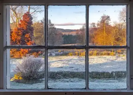 Frosty Scottish fields and a pink evening sky seen through a farmhouse window